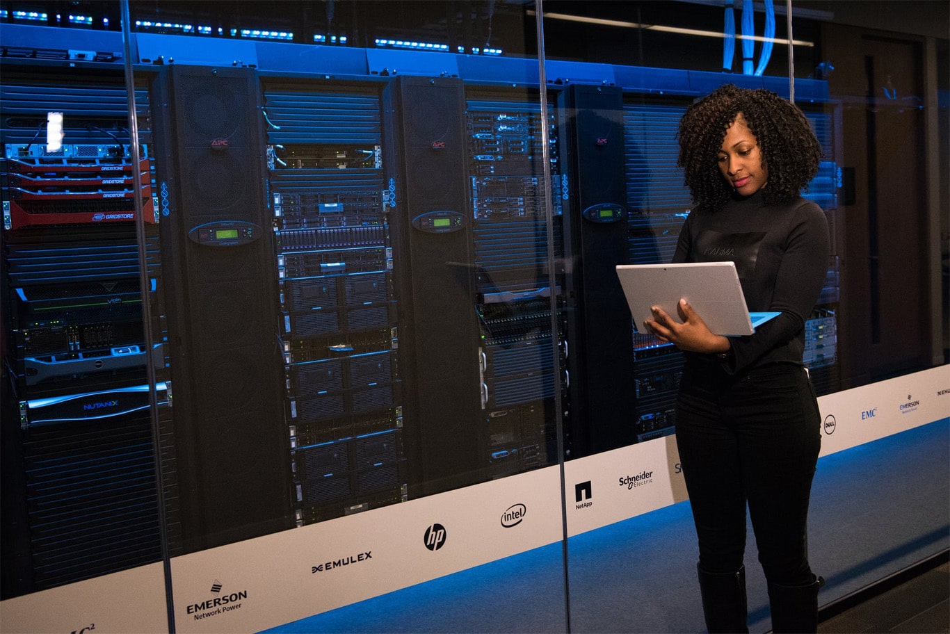 A woman holding a laptop inside a server room